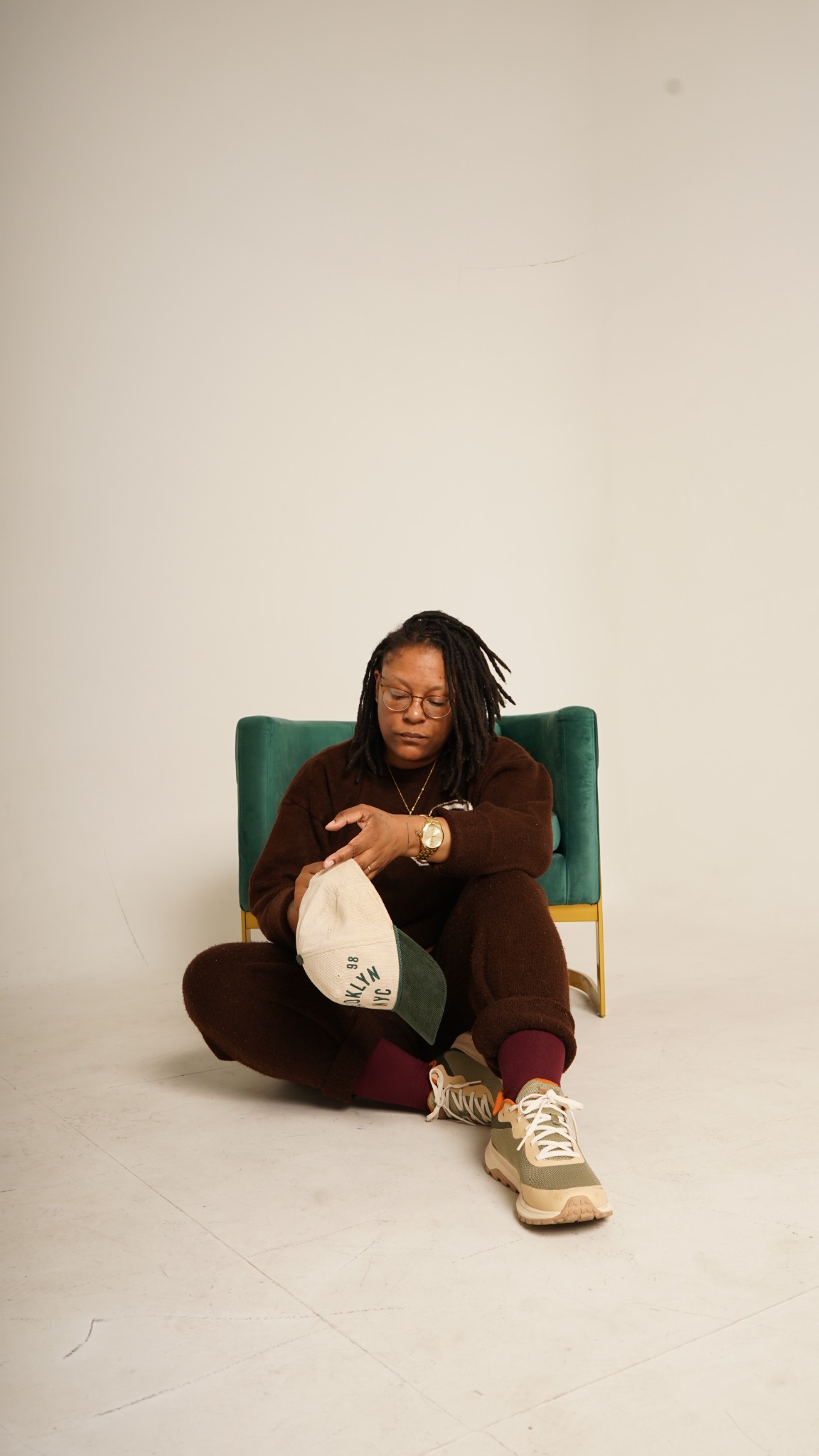 Lauren White, founder of Hudson Arts Collective, seated in front of a green chair